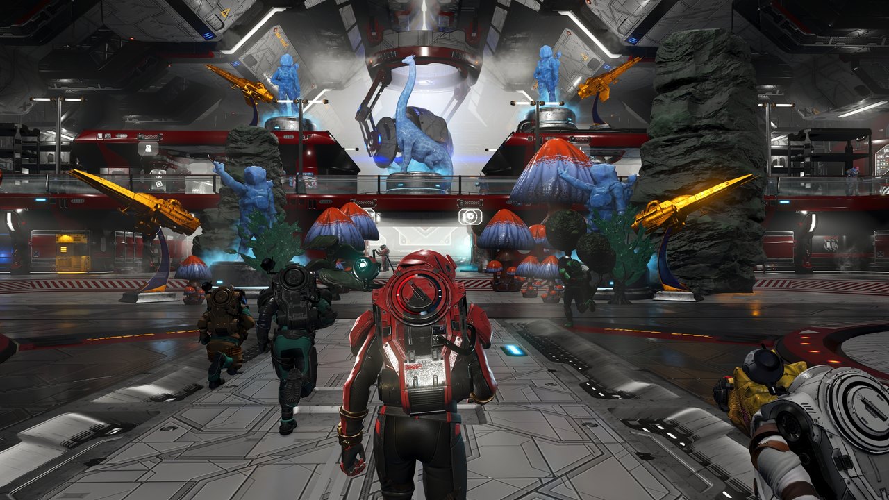 Four No Man's Sky players walking through a player owned space station decorated with statues
